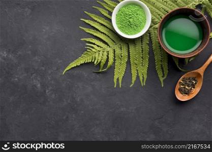 green match tea dry herb with fern leaves black textured background