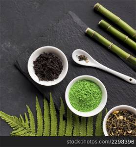 green matcha tea dry tea herb with bamboo stick black stone background