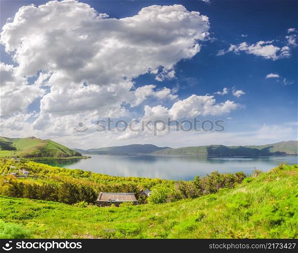 Green meadow, lake and blue sky with clouds. Meadow, lake and blue sky