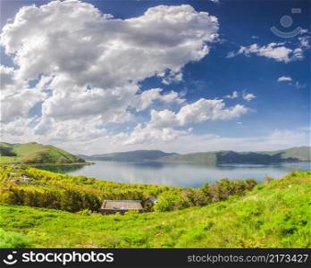 Green meadow, lake and blue sky with clouds. Meadow, lake and blue sky