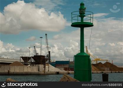 Green Metallic Lighthouse, Blue Sky with Clouds and Shipyard in Background