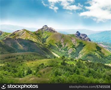 Green mountain covered with forest on the blue sky background. Panorama