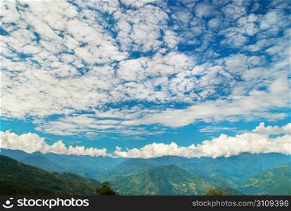 Green mountains with forest and blue cloudy sky