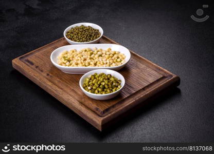 Green mung beans in a bowl on a dark concrete table. Legume plant for a healthy diet. Organics fresh Baby Green Bean Sprouts in white ceramic bowl on a dark concrete background