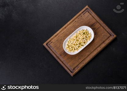 Green mung beans in a bowl on a dark concrete table. Legume plant for a healthy diet. Organics fresh Baby Green Bean Sprouts in white ceramic bowl on a dark concrete background