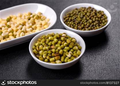 Green mung beans in a bowl on a dark concrete table. Legume plant for a healthy diet. Organics fresh Baby Green Bean Sprouts in white ceramic bowl on a dark concrete background
