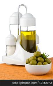 Green olives in a white ceramic bowl and oil decanter set.