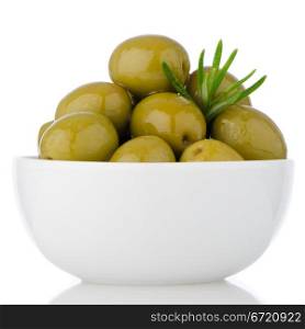 Green olives in a white ceramic bowl on white background.