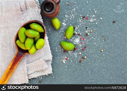 Green olives in a wooden spoon on a black background, top view