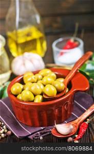 green olives in bowl and on a table