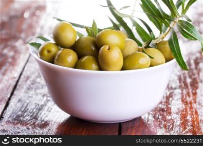 green olives with a branch on wooden table