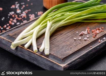 Green onion on a wooden board, fresh green onion. Green onion or scallion on wooden board, fresh spring chives