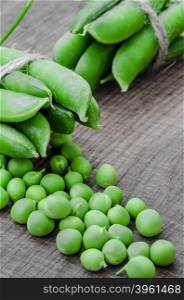 Green organic peas on wooden background, shalow focus