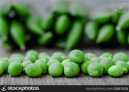 Green organic peas on wooden background, shalow focus