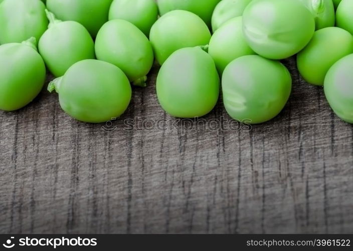 Green organic peas on wooden background, shalow focus