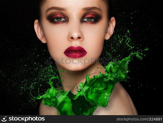 Green paint splash over beauty makeup fashion model girl with purple smokey eyes abstract on black background
