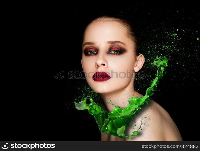 Green paint splash over beauty makeup fashion model girl with purple smokey eyes abstract on black background