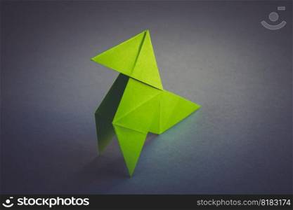 Green paper hen origami isolated on a blank grey background. Cocotte en papier. Green paper hen origami isolated on a grey background