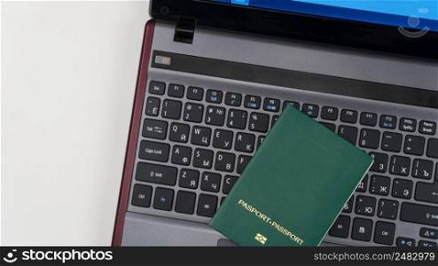 green passport on the laptop keyboard. Online registration. Top view. green passport on the keyboard
