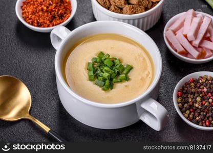 Green pea cream soup with crackers. Vegetarian healthy soup. Cream soup with potatoes, leek and peas on a dark concrete table