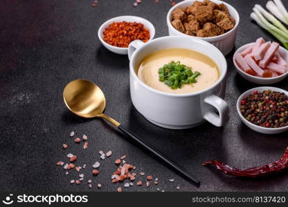 Green pea cream soup with crackers. Vegetarian healthy soup. Cream soup with potatoes, leek and peas on a dark concrete table