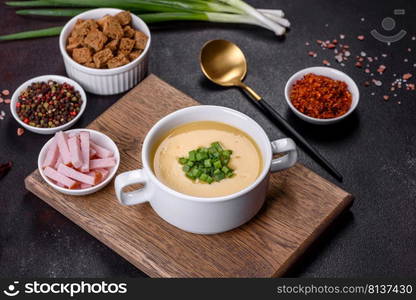 Green pea cream soup with crackers. Vegetarian healthy soup. Cream soup with potatoes, leek and peas on a dark concrete table