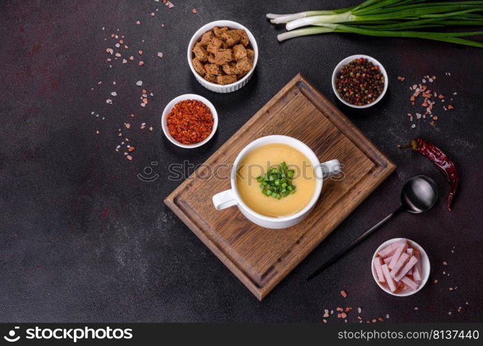 Green pea cream soup with crackers. Vegetarian healthy soup. Cream soup with potatoes, leek and peas on a dark concrete table