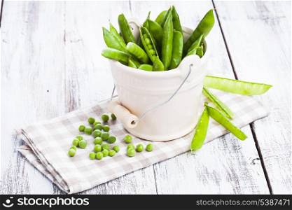 Green pea scattered on the napkin and unpeeled pea