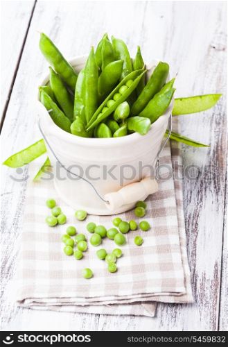 Green pea scattered on the napkin and unpeeled pea