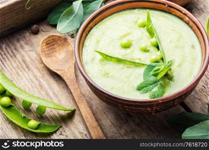 Green pea soup on wooden rustic table. Pea cream soup.