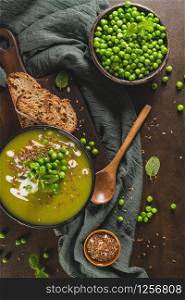 Green pea soup with linseed and pumpkin and sunflower seeds on a rustic kitchen countertop.