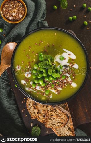 Green pea soup with linseed and pumpkin and sunflower seeds on a rustic kitchen countertop.