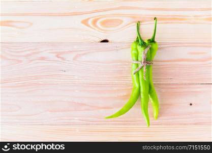 Green peppers are tied together on a wooden plate.