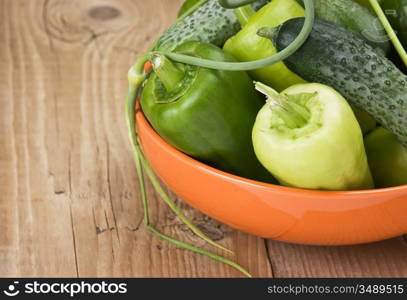 green peppers, cucumbers and garlic in a bowl on a wooden table