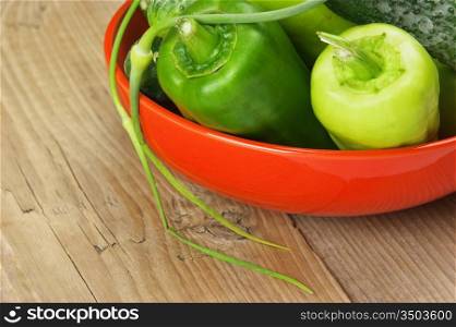 green peppers, cucumbers and garlic in a bowl on a wooden table