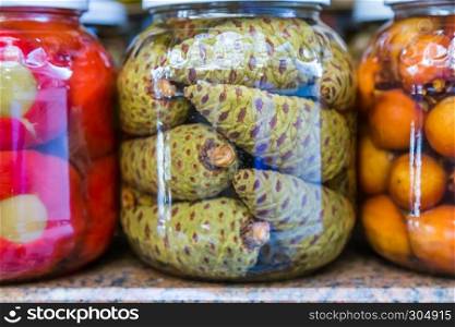 Green pine cones pickles are in glass jar display for sale. Green pine cones pickles are in glass jar