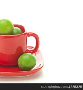 green plum in the red cup isolated on white