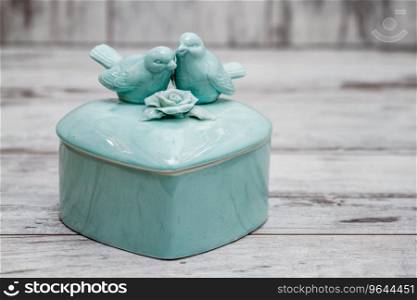 Green porcelain box with birds and flowers on white wooden background