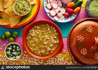 Green Pozole verde with blanco mote corn and ingredients on colorful table
