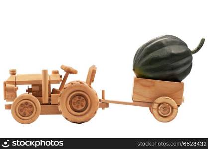 Green pumpkin in wooden toy tractor cart, isolated on white background.