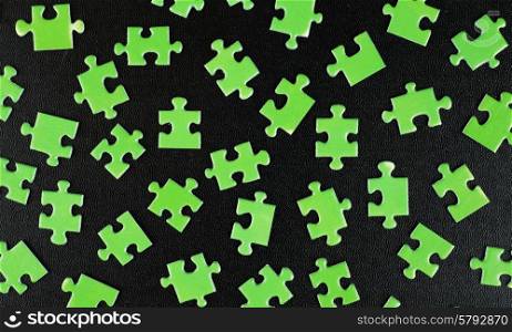 Green puzzles on a black leather background