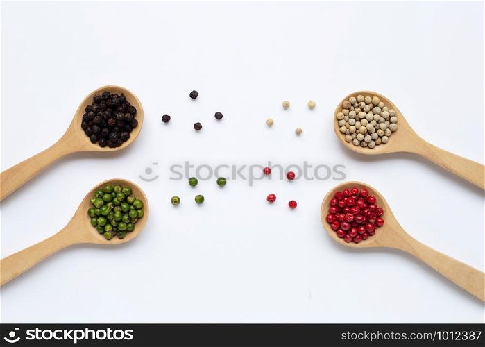 Green, red, white and black peppercorns with wooden spoon on white background.