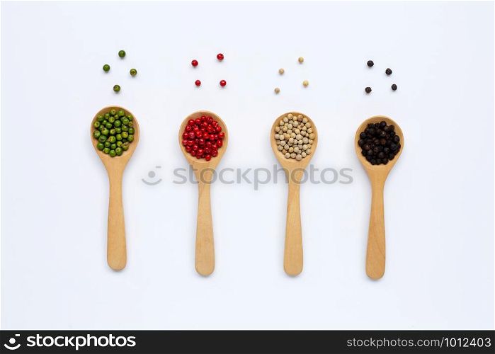 Green, red, white and black peppercorns with wooden spoon on white background.