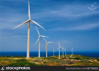 Green renewable alternative energy concept - wind generator turbines generating electricity. Wind farm on Crete island, Greece with road. Wind generator turbines. Crete island, Greece