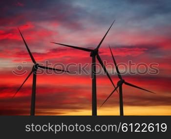 Green renewable energy concept - wind generator turbines in sky on sunset. Wind generator turbines in sky