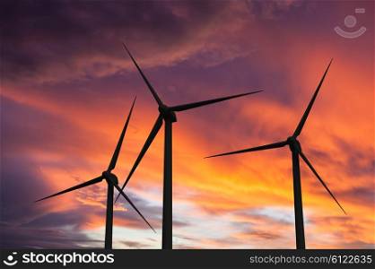 Green renewable energy concept - wind generator turbines in sky on sunset. Wind generator turbines in sky