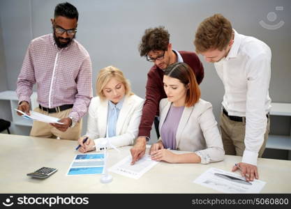 green renewable energy, teamwork, corporate and people concept - business team with papers and wind turbine model meeting and discussing project at office. business people discussing green energy project