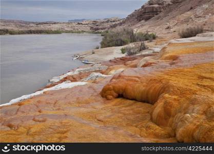 Green River at Crystal Geyser below town of Green River, Utah - a shore covered with orange mineral deposits, two kayaks