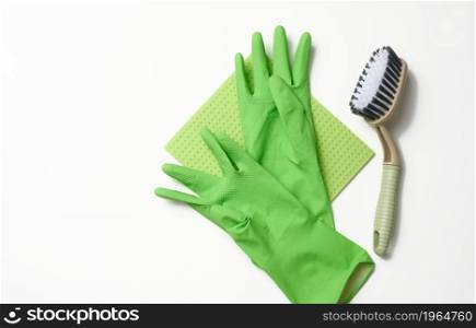 green rug, rubber gloves for cleaning, brushes on a white background, flat lay.