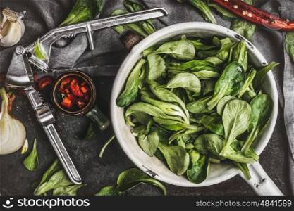 Green salad leaves in vintage colander on rustic kitchen table, top view